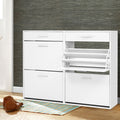 White wide shoe cabinet two drawers and four flip-out compartments right middle tray open in hallway with textured wallpaper