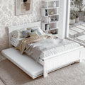 White wooden bed frame with trundle extended in bedroom with floral wallpaper and white zigzag bookshelf in background