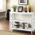 White console table with X-frame sides and two open shelves in room; styled with plant, photo frame, amber vases and books