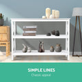 White X-frame console table with shelves styled with cream vases, books and ceramic figurines; text 
