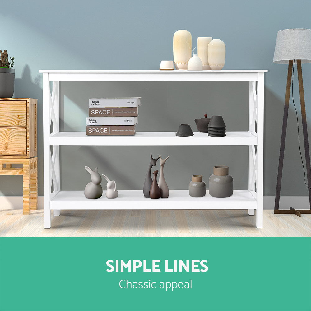 White X-frame console table with shelves styled with cream vases, books and ceramic figurines; text "Simple lines"